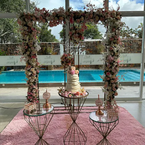 Cumpleaños con arco de flores y torta, frente a la piscina