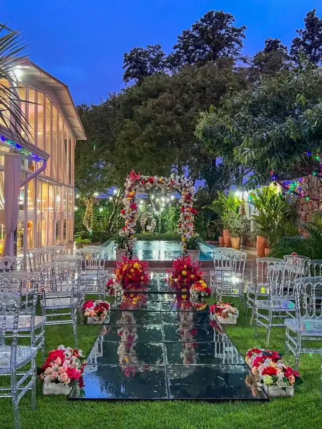 Ceremonia al anochecer en el jardín, con pasarela de espejo y el salón iluminado
