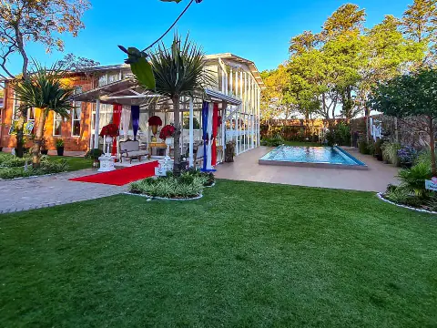Vista del predio: césped, piscina, el salón vidriado y la casona de ladrillo