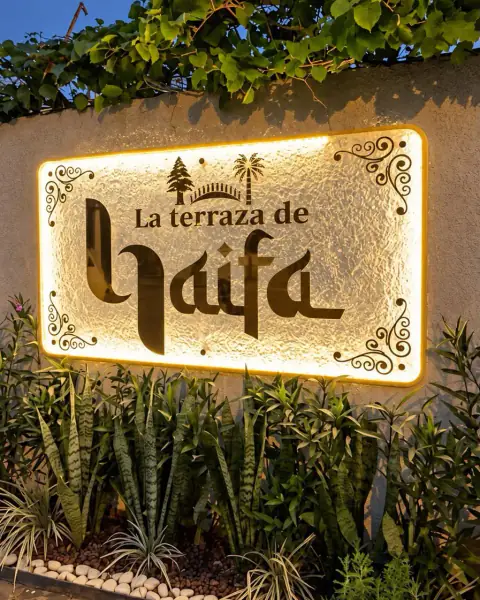 El cartel iluminado de La Terraza de Haifa en la entrada, de noche