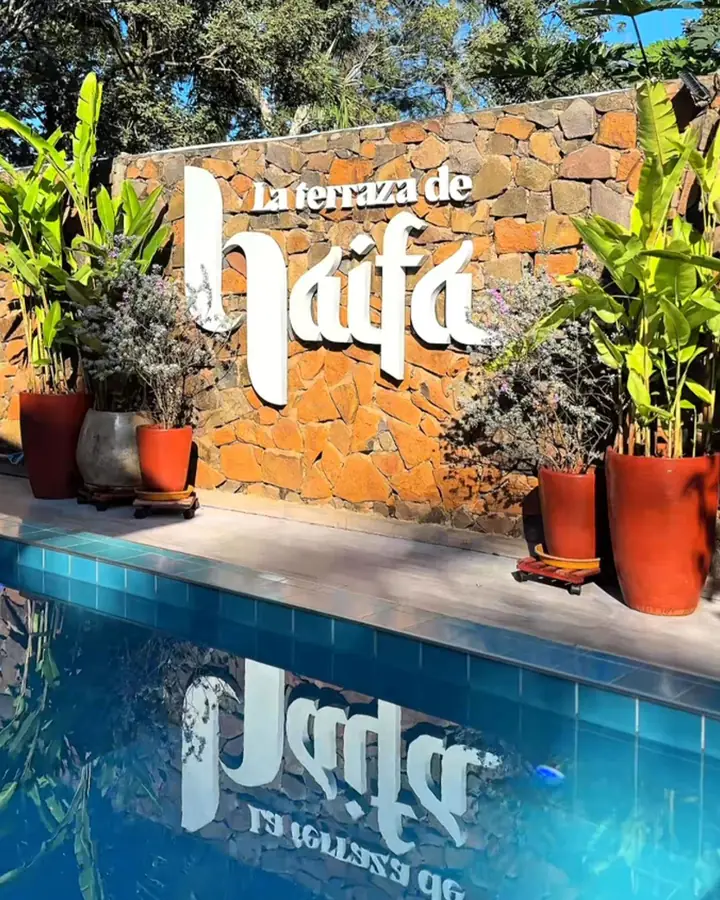 Las letras blancas del muro de piedra reflejadas en la piscina