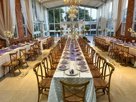Salón armado con mesas largas y sillas de madera